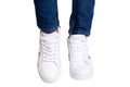 Women legs in jeans and sneakers. Woman legs in blue denim pants wearing modern white sneaker. Fashionable white footwear. Macro