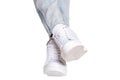 Women legs in jeans and sneakers. Woman legs in light denim pants wearing modern white sneaker. Fashionable white footwear. Macro Royalty Free Stock Photo