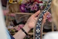 Women is looking at handmade weaved belt. Ornamental Latvian be
