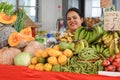 Women looks smiling from behind her counter stacked high with fresh fruit and vegetables in Farmers and craft market in Fiji Royalty Free Stock Photo