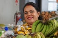 Women looks smiling from behind her counter stacked high with fresh fruit and vegetables in Farmers and craft market in Fiji