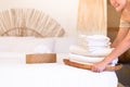 Woman maid hands putting stack clean towels white color on bed in hotel