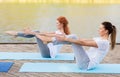 Women making yoga in half-boat pose outdoors