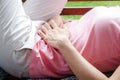 Women with menstrual pain lie on a wooden chair in the house.