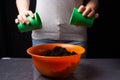 Women mixing ground with minerals in container for plant