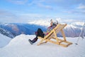 Woman drinking warm tea in the rustick wooden terrace on mountain, alpine view, snow on hills