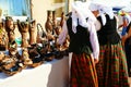 Women with national costumes buys handmade clay pots.