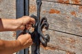 Women opens an ancient wooden door decorated with wrought iron elements. Royalty Free Stock Photo