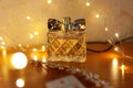 Women parfume Avon in glass clear bottle near golden bride accessories for hair and blurred lights
