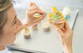 women in pastry bakery as confectioner draped candy pearl topping on a colorful muffin with tweezers Royalty Free Stock Photo