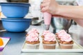 Women in pastry bakery as confectioner glazing muffins with icing