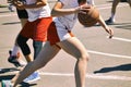 Group of happy teenage girls in sports uniform, playing basketball outdoors in the city.