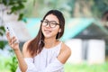 The women play phone in the park and wear white dress. She is smile and wear earphone. Royalty Free Stock Photo