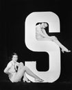 Women posing with huge letter S Royalty Free Stock Photo