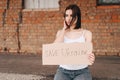 Women with Poster Save Ukraine. A woman with belligerent look looks to the side. Wind develops Hair