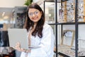 women professional optician selling checking details of glasses and holding laptop in optical shop. Female optician accessory