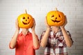 Women with pumpkin heads near white wall. Jack lantern - traditional Halloween decor