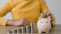 Women put coins in pink piggy banks with increasing coins stacked on the table, Money saving and deposit for investment to get Royalty Free Stock Photo