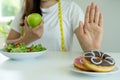 Women reject junk food or unhealthy foods such as doughnuts and choose healthy foods such as green apples and salads. Concept of f