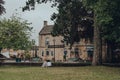 Women relax by The Kingsbridge Inn and pub along River Windrush in Bourton-on-the-Water, Cotswolds, UK