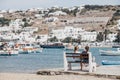 Women relaxing on a bench by the water on a sunny day in Hora Mykonos Town, Mykonos, Greece