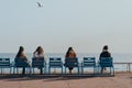 Women relaxing on blue chairs on The Promenade des Anglais in Nice, France, on a sunny spring day