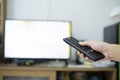 The women with the remote control in hand watching the channel and presses the button on the remote control Royalty Free Stock Photo