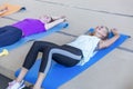 Women rest on mats in the gym after a workout. Young beauties in bright sportswear. Activity and joy of movement Royalty Free Stock Photo