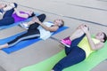 Women rest and stretch their muscles on mats in the gym after a workout. Young beauties in bright sportswear. Activity and joy of Royalty Free Stock Photo