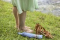 Women's bare feet on the green grass next to the shore of the lake. Nearby are sandals and an umbrella