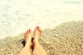 Women`s bare feet on a pebble beach near the sea on a sunny day. Royalty Free Stock Photo