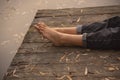 Women`s bare feet on the wooden deck, strewn with autumn leaves Royalty Free Stock Photo