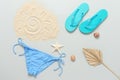 Women`s beach accessories. Beach composition on a gray background. Bikini, flip flops, starfish, seashells, sand and palm leaf fa Royalty Free Stock Photo