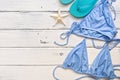 Women`s beach accessories - blue bikini swimsuit and flip flops on a white wooden background. Top view, flat lay, copy space Royalty Free Stock Photo