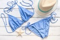 Women`s beach accessories blue bikini swimsuit and straw hat on a white wooden background. View from above Royalty Free Stock Photo