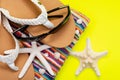 Women`s Beach Flip Flops, Colorful Striped Beach Towels and black Sunglasses decorated with Starfish on yellow background Royalty Free Stock Photo