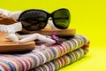 Women`s Beach Flip Flops, Colorful Striped Beach Towels and black Sunglasses decorated with Starfish on yellow background Royalty Free Stock Photo