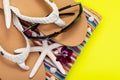 Women`s Beach Flip Flops, Colorful Striped Beach Towels and black Sunglasses decorated with Starfish on yellow background Royalty Free Stock Photo