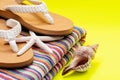 Women`s Causal natural color Beach Flip Flops and Colorful Striped Beach Towel decorated with White Finger Starfish and Seashells Royalty Free Stock Photo