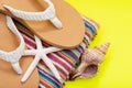 Women`s Causal natural color Beach Flip Flops and Colorful Striped Beach Towel decorated with White Finger Starfish and Seashells Royalty Free Stock Photo