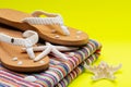 Women`s Causal natural color Beach Flip Flops and Colorful Striped Beach Towel decorated with White Finger Starfish and Seashells Royalty Free Stock Photo