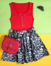 Women's clothes and accessories on a colored background. Skirt, T-shirt, leather bag, hair clip, top view.