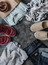 Women`s clothing on a dark background, top view. Shopping concept. Autumn women`s clothing - jeans, suede shoes, sneakers,