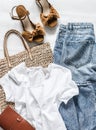 Women`s clothing summer - mom`s jeans, suede brown wedge sandals, white cotton t-shirt, eco bag straw on a light background, top Royalty Free Stock Photo