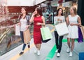 Women`s company is in mall. They are split on two groups. Girl in red dress is talking on the phone while asian girl is Royalty Free Stock Photo