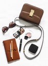 Women`s cross body brown leather bag, business organizer, cosmetics and sunglasses on a light background, top view. Fashion beaut