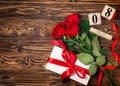 Women`s day background. 8 march wooden calendar, red roses, gift with red ribbon on the wooden background. Copy space, flat lay