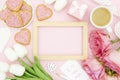 Women\'s day day greeting card mockup. Heart shaped cookies, tulips and cup of coffee on pink background Royalty Free Stock Photo