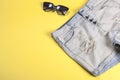 Women`s denim shorts with frayed close-up on a yellow background and sunglasses, summer version of clothing for a young girl Royalty Free Stock Photo