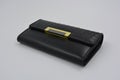 Women`s elegant black wallet with gold and metal inserts and adornment. Exquisite leather goods, natural leather wallet, portman.